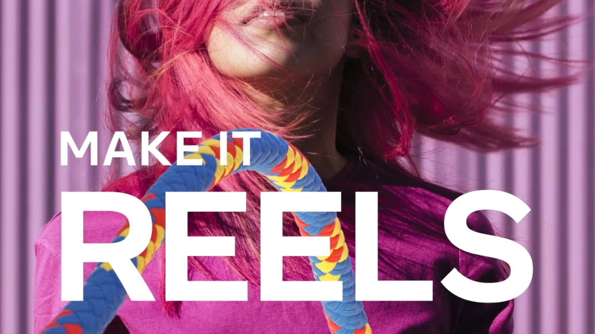 Woman with vibrant pink hair stands against a striped background, with bold text "MAKE IT REELS" for a social media campaign.